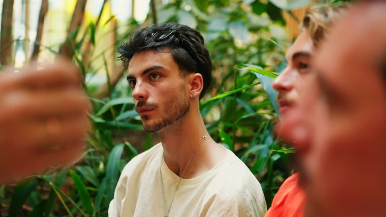 Jongeman met zonnebril en chain ketting die in de verte kijkt.