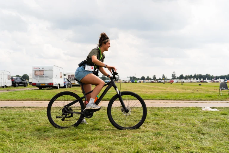 New Nomads medewerker Fleur op de fiets op het festival terrein.