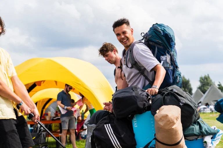 Knipoog man met allerlei tassen en koffers.